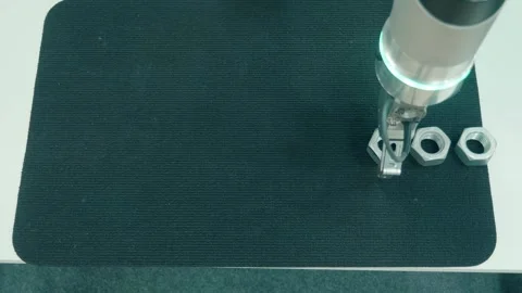 The robot arm moves nuts from one place to another according to the program Stock Footage 333360743