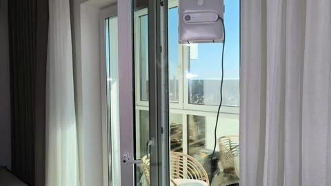 Robot cleaner sprays liquid on window and moves across transparent surface... Vídeo Stock 333143797