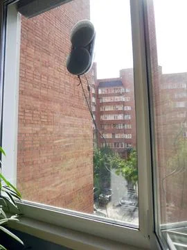 Robot Cleans Windows: Balcony View of City Buildings Fotos de archivo
