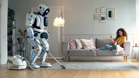 A robot does vacuum cleaning while a girl lying on a couch. Cyborg and human Stock Footage 113155660
