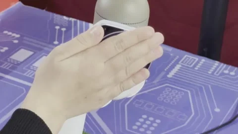 A robot with a face on it is being touched by a hand Stock Footage 279823459