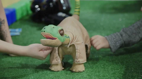 Robot in the form of a dinosaur. Children's hands touch the it Video stock 85927118