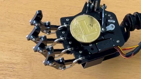 A robot hand grips a Litecoin, symbolizing the rise of automation and AI in Stock Footage 306804781