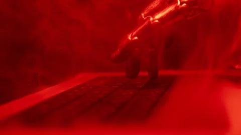 A robot hand types on a laptop keyboard in red. Haze above the computer, a pink Stock Photos