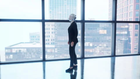 A robot humanoid staying in the empty office and looking out the window at the Stock Footage 255677562