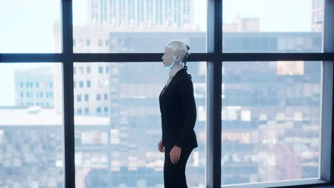 A robot humanoid staying in the empty office and looking out the window at the Stock Footage 255785358