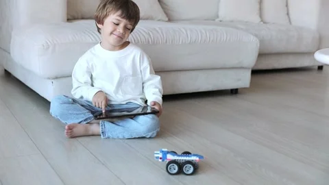 Robot made of bricks is controlled by a kid programmer, who uses tablet pc Stock Footage 254615654
