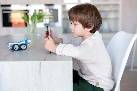 Robot made of bricks is controlled by a kid programmer, who uses tablet pc Stock Photos