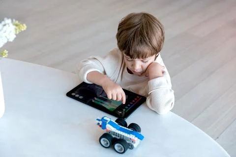 Robot made of bricks is controlled by a kid programmer, who uses tablet pc Stock Photos
