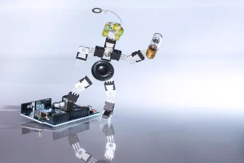 Robot from microcircuits with a light bulb in hands comes off the board for i Stock Photos