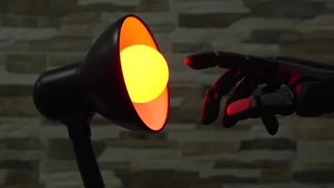 Robot or Prosthesis Hand Touching Glowing Smart Bulb in Desk Lamp Stock Footage 339241526