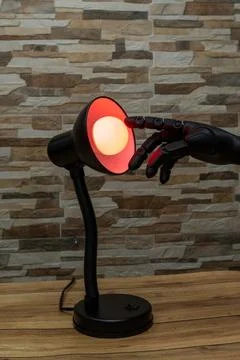 Robot or Prosthesis Hand Touching Glowing Smart Bulb in Desk Lamp Stock Photos