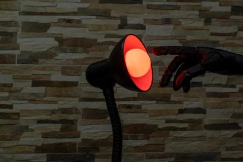 Robot or Prosthesis Hand Touching Glowing Smart Bulb in Desk Lamp Stock Photos