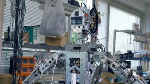 A robot with a screen on its head repeats programmed arm movements. 4K. Stock Footage 80075648