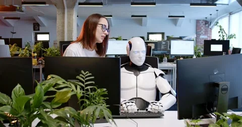 Robot sitting at table in office, typing on keyboard. Woman talking and helping Stock Footage 180026826