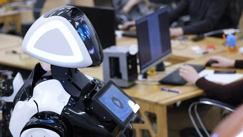 The robot stands next to the programmer. A human programmer works at a computer. Stock Footage 102179052