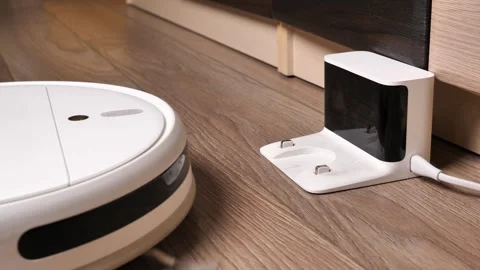 The robot vacuum cleaner arrived at its station. cleaning at home with a ro.. Video stock 254610192