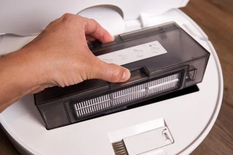 Robot vacuum cleaner being serviced with dustbin removal at home on a woode.. Stock Photos