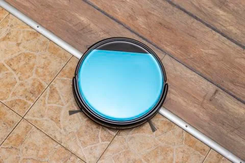 Robot vacuum cleaner between two floor surfaces Stockfoto's