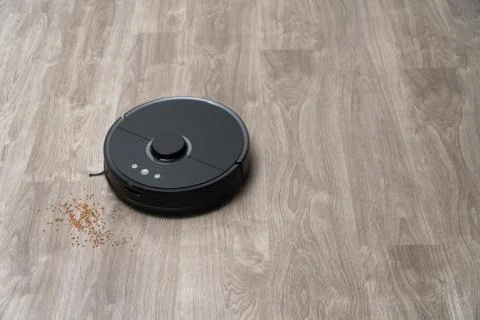 Robot vacuum cleaner black on the floor is cleaning, gray laminate Stock Photos
