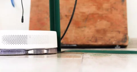 Robot vacuum cleaner carefully removes hair near the leg of a folding table  Stock Footage 307828231