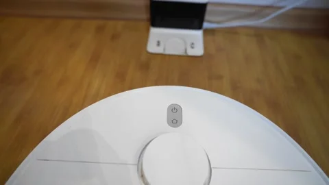 Robot vacuum cleaner on charging dock on wooden floor, smart home device Stock Footage 324505173