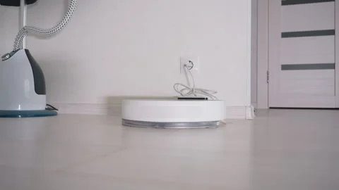 Robot Vacuum Cleaner Charging on Floor Near Wall Socket Stock Footage 320019956