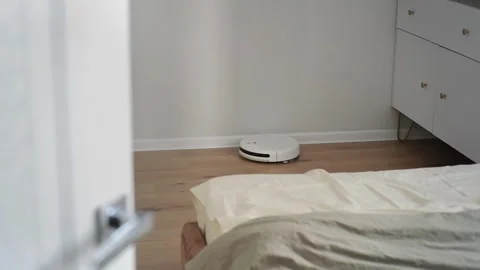 Robot vacuum cleaner cleans the floor in a bedroom Stock Footage 303484431