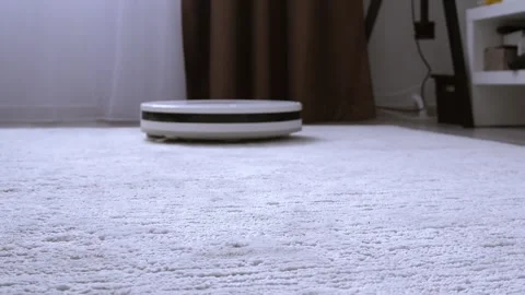 Robot vacuum cleaner drives and cleans the apartment on the carpet. Stock Footage 306168089