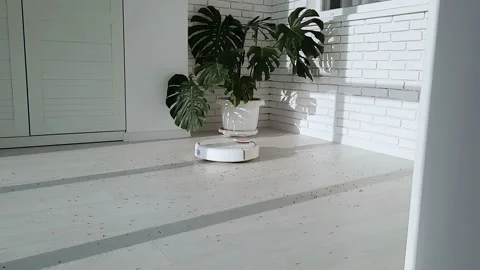 The robot vacuum cleaner drives on the laminate floor. Stock Footage 147451618