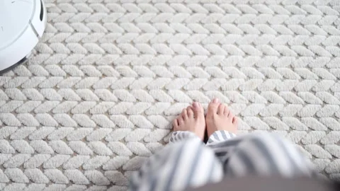 Robot vacuum cleaner driving around barefoot woman at home. Stock Footage 328034805
