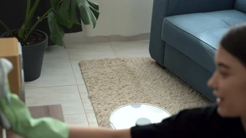 Robot vacuum cleaner helping young woman to keep house neat Stock Footage 196596927