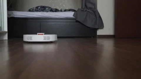 Robot vacuum cleaner in a modern interior cleans the room, dusts in the bedro Stock Footage 177525739
