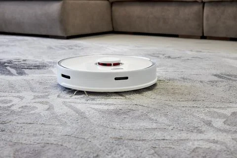 The robot vacuum cleaner performs automatic carpet cleaning Stock Photos