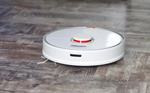 Robot vacuum cleaner performs automatic cleaning on wooden floor Stock Photos