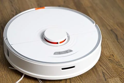 Robot vacuum cleaner performs automatic cleaning on wooden floor Stock-Fotos