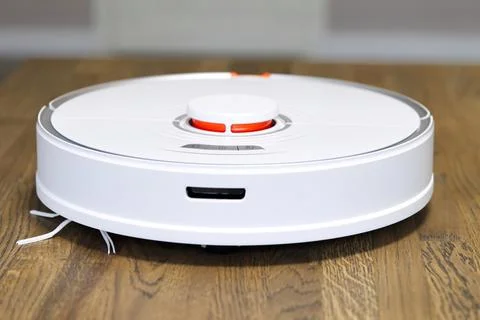 Robot vacuum cleaner performs automatic cleaning on wooden floor Stock Photos