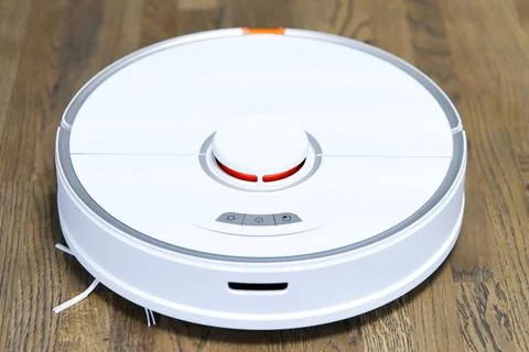 Robot vacuum cleaner performs automatic cleaning on wooden floor Stock Photos