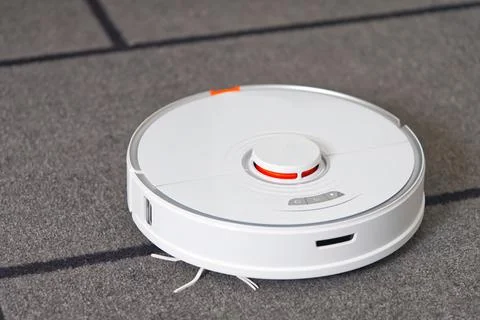 Robot vacuum cleaner performs automatic cleaning on carpet. Stock Photos