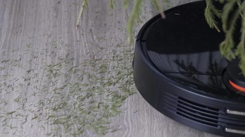 A robot vacuum cleaner removes the fallen needles from the Christmas tree. Stock Footage 169020609