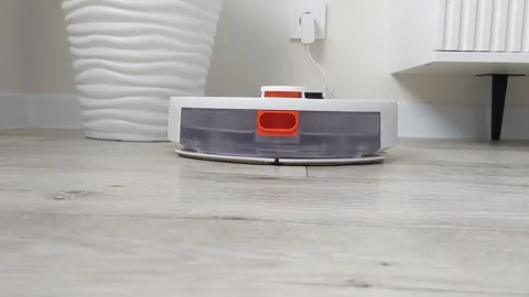 The robot vacuum cleaner returning to the base for charging. Stock Footage 300663623