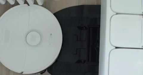 Robot vacuum cleaner started cleaning in a living room on floor from charging Stock Footage 252173507