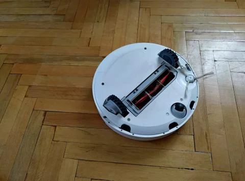 Robot vacuum cleaner upside down for cleaning and repair on a light floor Stock Photos