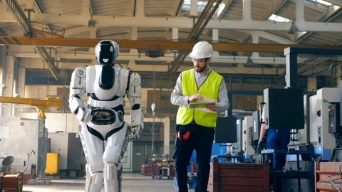 Robot is walking along the factory under control of a male specialist Video stock 107932732