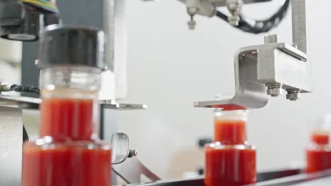 Robotic arm capping hot sauce bottles on automated production line Stock Footage 321802814