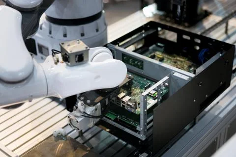 Robotic arm installing a computer chip in factory. Industrial and factory wit Stock Photos
