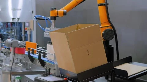 Robotic arm manipulator moves and loads plastic bottles into cardboard box Stock Footage 344342381