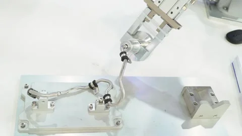 Robotic arm tightens nuts on bent metal pipe with precision at an industrial Stock Footage 310884991