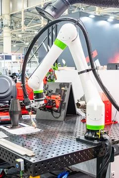 Robotic arm welding over perforated metal workbench, cylindrical object, pa.. Stock Photos