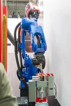 Robotic arm with welding torch, mounted on red base, set against clean whit.. Stock Photos